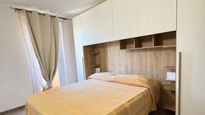 Een slaapkamer met een bed, een houten hoofdeinde, een kledingkast en een nachtkastje.