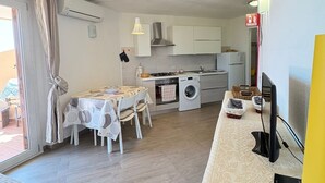 A compact living space with a kitchenette, a dining area, and a bed. - New valmar Two-room apartment 56 - Via del Lentischio (Costa Rei)