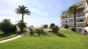 A well-maintained grassy area with palm trees and a pathway leading to a building with balconies. - Acapulco Playa 308 by Casasol (Nerja)