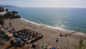A beach with umbrellas, lounge chairs, and a view of the ocean. - Acapulco Playa 308 by Casasol (Nerja)
