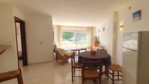 Un espace repas comprenant une table et des chaises, un réfrigérateur et une vue sur l’extérieur.