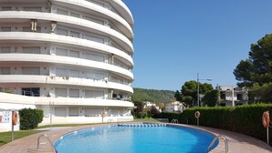 Un immeuble moderne à plusieurs étages, avec une piscine située devant.