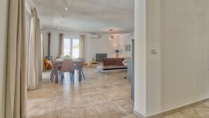 Ein geräumiger Wohnbereich mit Esstisch, Stühlen, einer Couch und einem Fernseher.