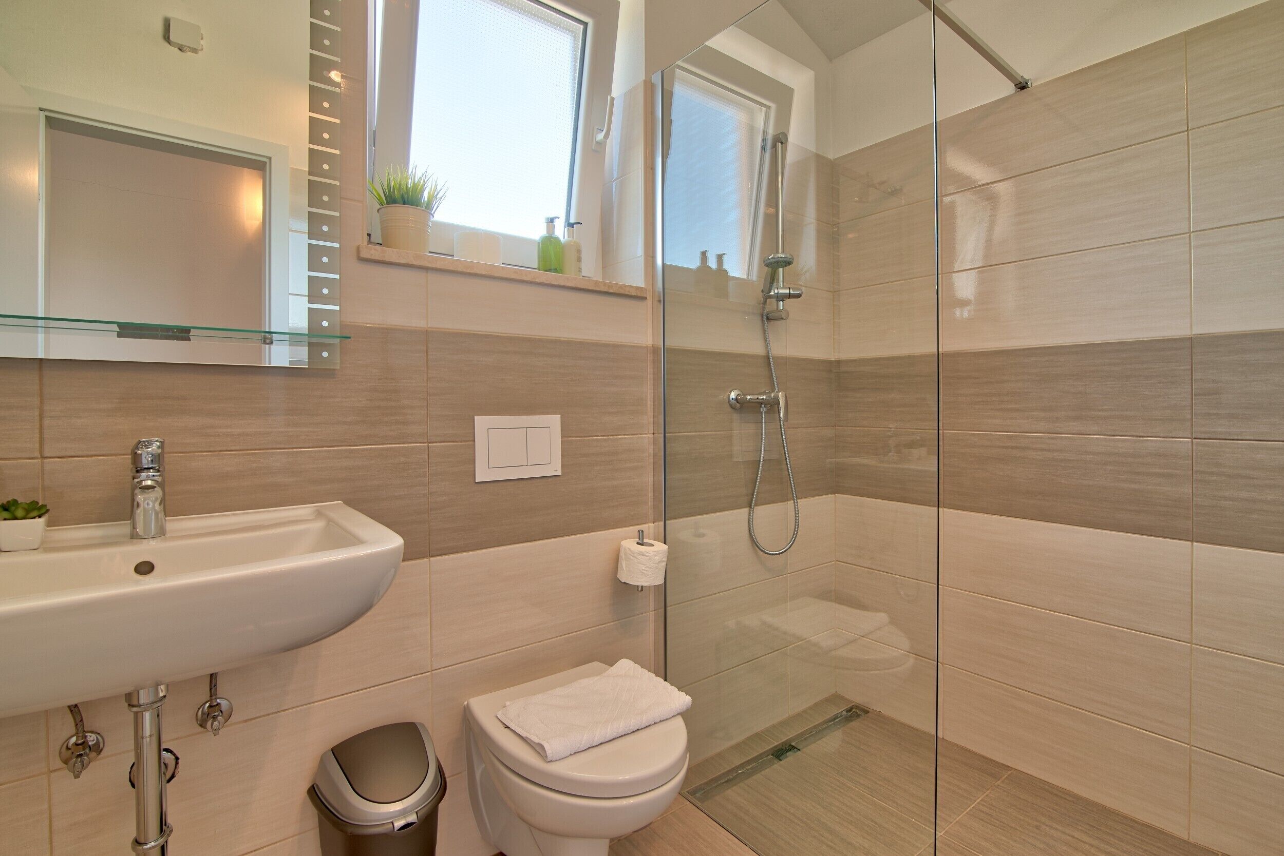 Un baño moderno con cabina de ducha de vidrio, un lavabo con espejo y un inodoro.