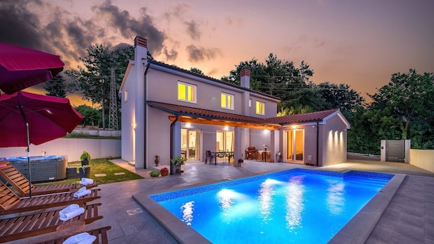 Ein modernes Haus mit Swimmingpool, Sitzgelegenheiten im Freien und einer Terrassenfläche.