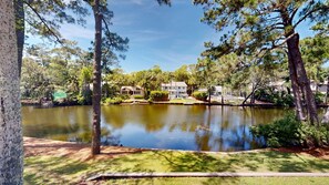 Un lago con un muelle, rodeado de árboles y casas.