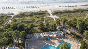 Un resort con piscina, acceso a la playa y palmeras.