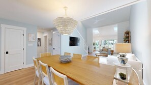 A dining area with a wooden table and chairs, a chandelier, and a view of the living room. - Recently Renovated Lagoon View Townhouse! (Hilton Head)