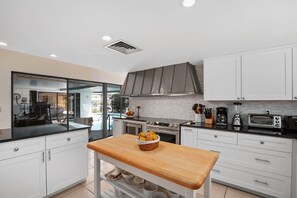 Enjoy cooking in this well-equipped kitchen with a stove, oven, microwave, and toaster, and take in the view of the outdoor pool.