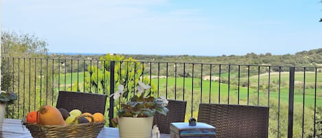 Ein Tisch mit Obstkorb, Blumentopf und einer dekorativen Schachtel auf einem Balkon mit Blick auf einen Golfplatz.