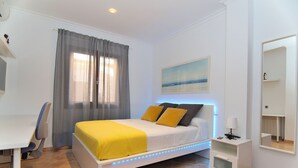 Ein Schlafzimmer mit Bett, Schreibtisch, Stuhl, Nachttisch und Spiegel.