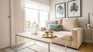 A modern living room with a beige sofa, a coffee table with decorative items, and two framed leaf artworks on the wall.