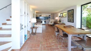 Une cuisine moderne avec un îlot central, un coin repas avec une table et des chaises en bois, et un escalier situé sur le côté gauche.