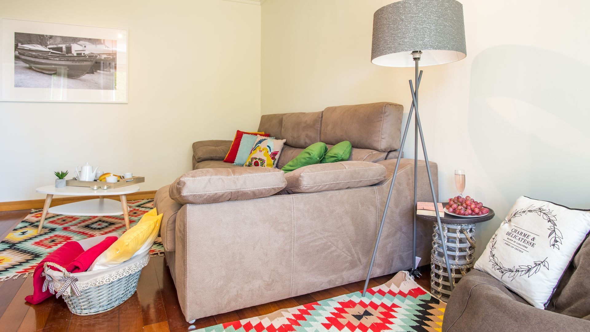 A cozy living room with a sofa, a floor lamp, a basket, and a patterned rug.