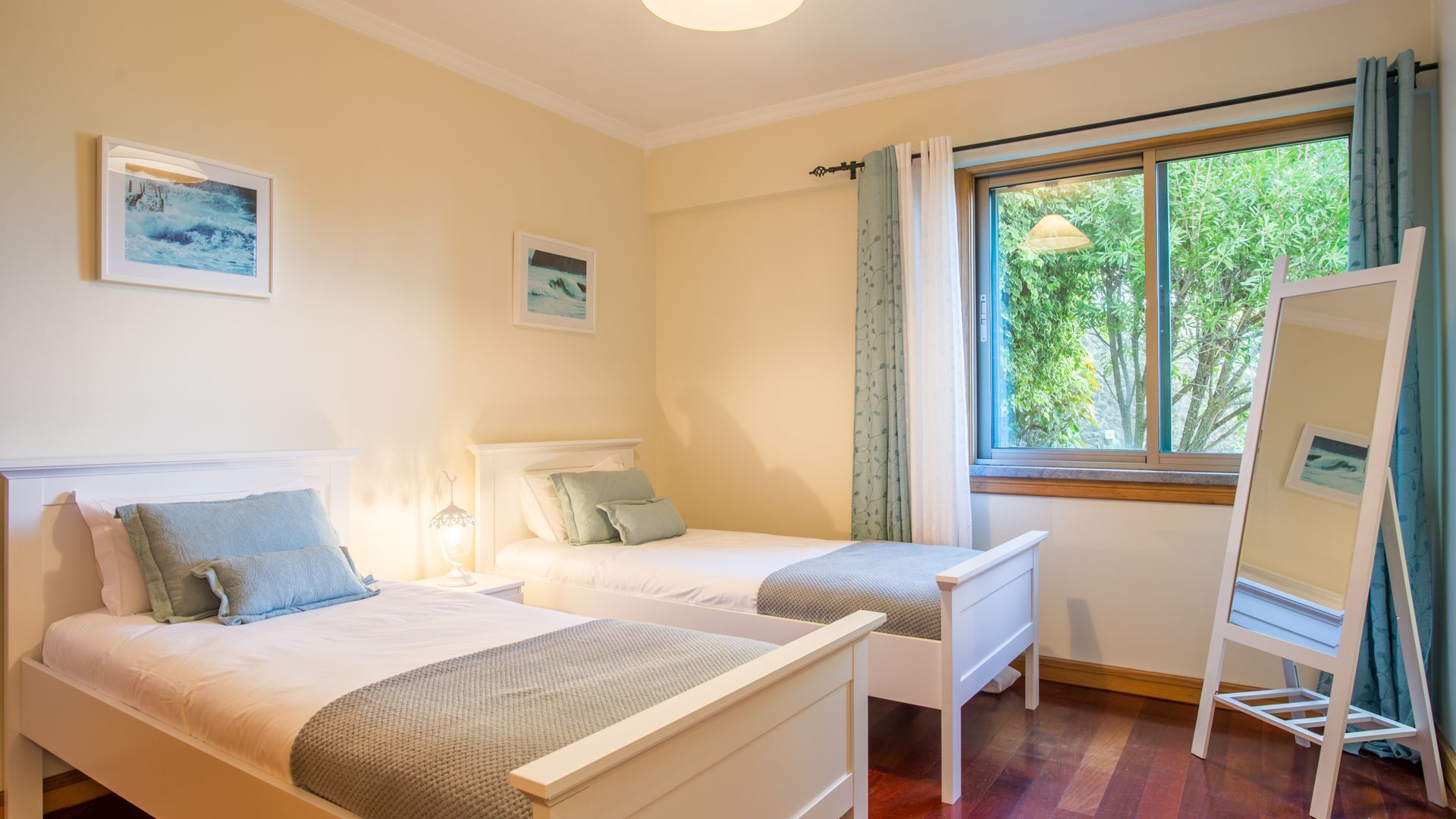 Une chambre avec deux lits simples, une fenêtre avec des rideaux et une petite table avec une lampe.