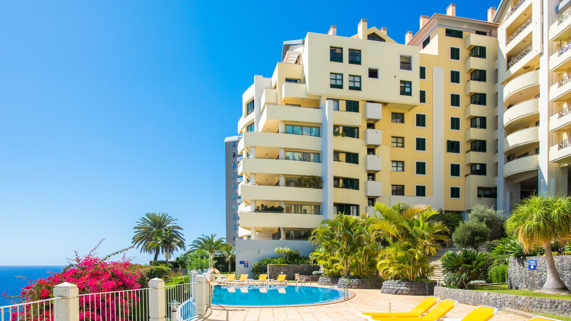 Hotel de diversos pisos amb zona de piscina, incloent una piscina, gandules i vistes al mar.