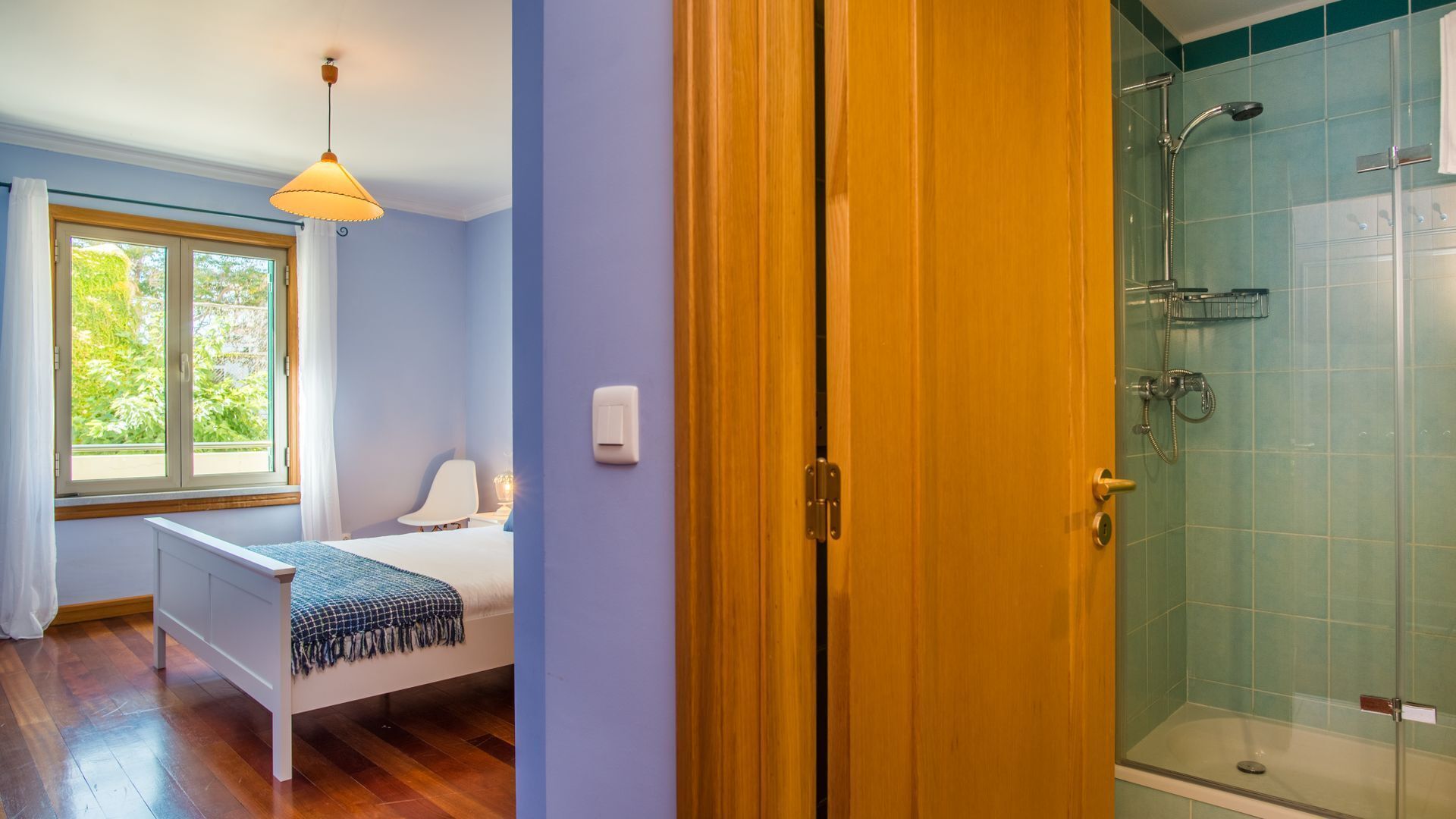 A bedroom with a bed, a window, and a bedside table.