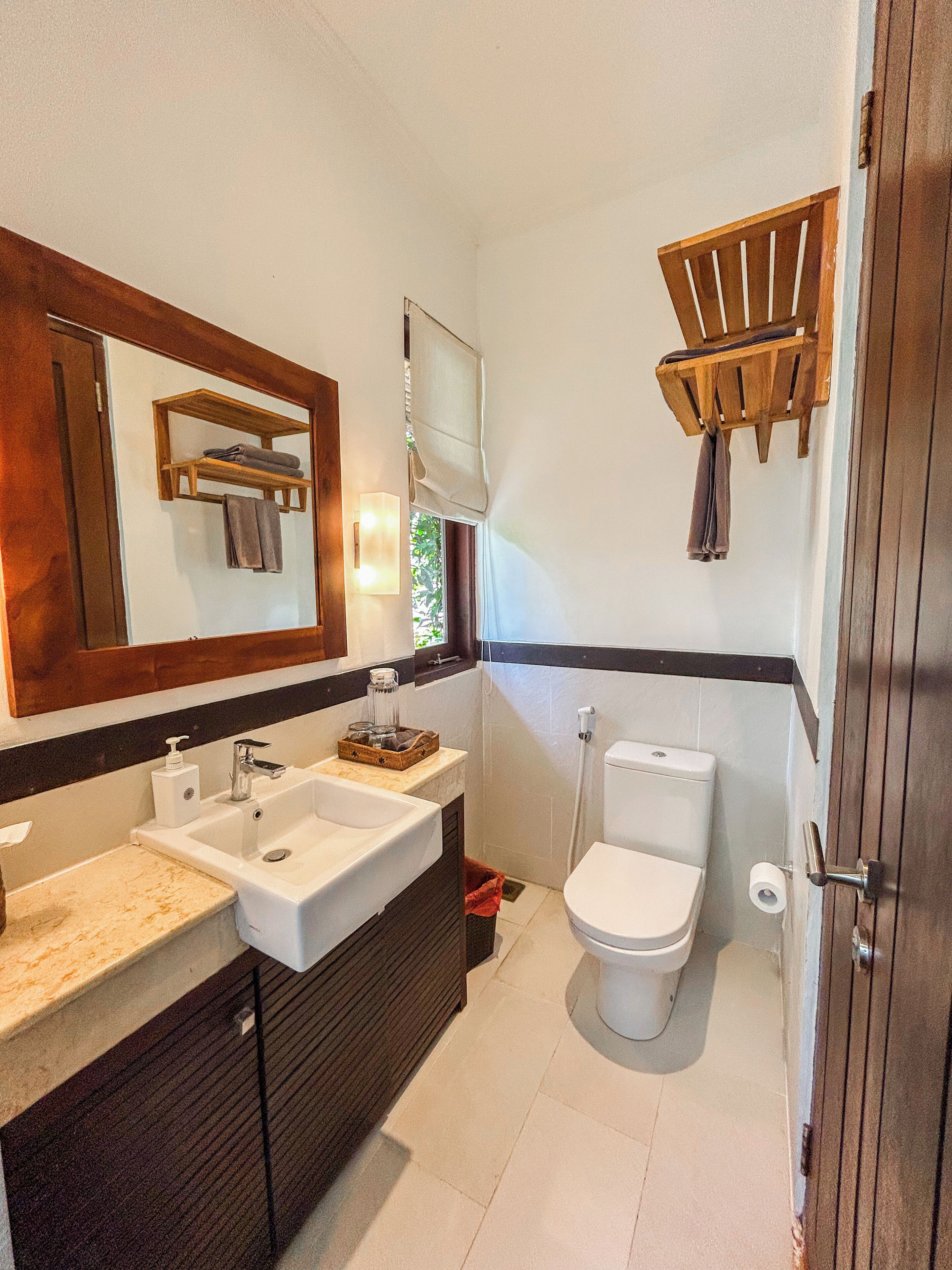 A bathroom with a double sink, a toilet, a mirror, and a towel rack.
