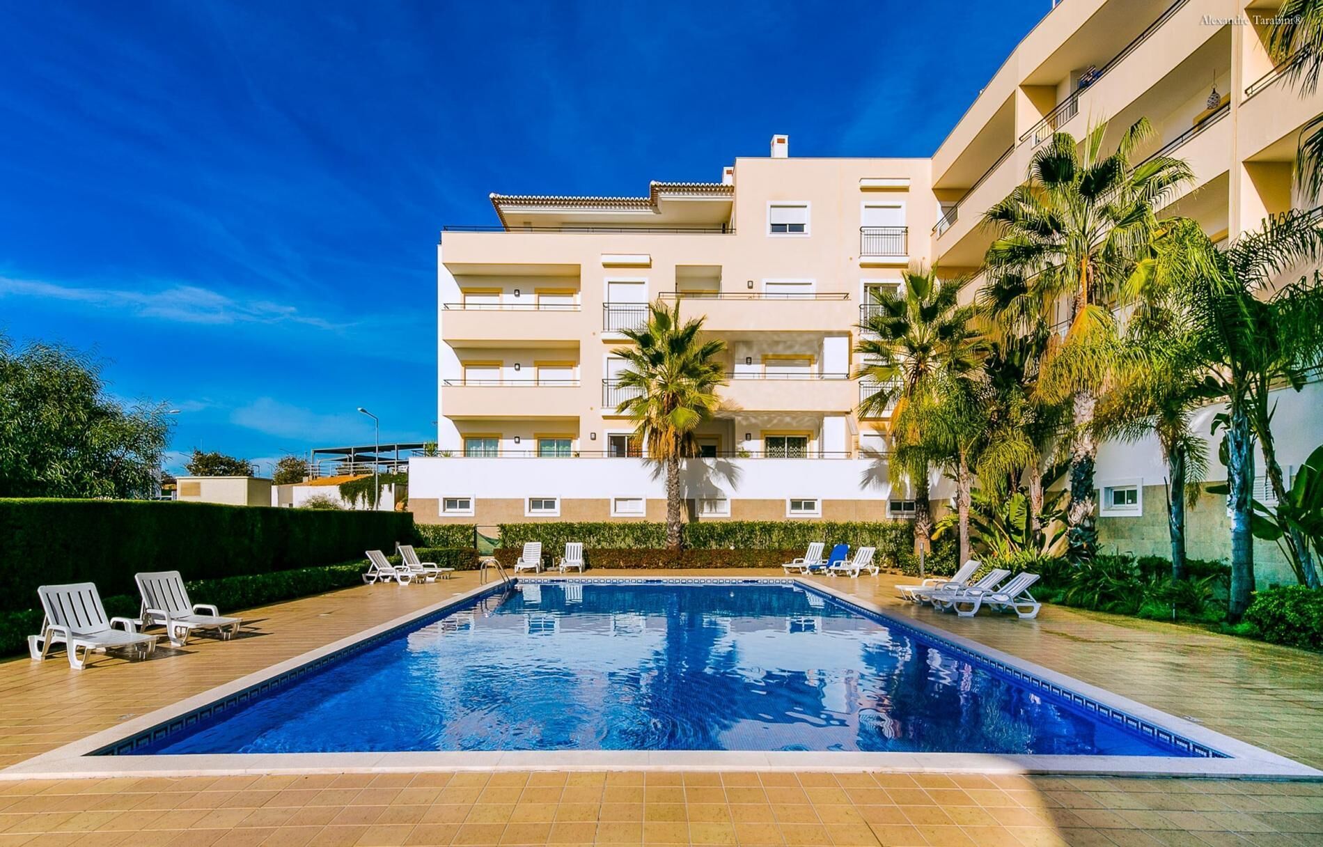 Un hôtel doté d’une piscine, de nombreux balcons et de palmiers.