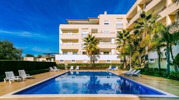 Un hôtel doté d’une piscine, de nombreux balcons et de palmiers.