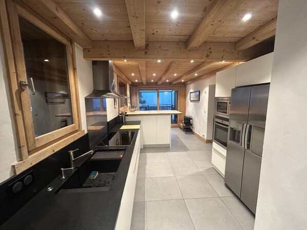 Une cuisine moderne avec des poutres en bois, un îlot central et des appareils électroménagers intégrés.