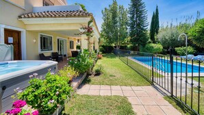 A poolside area with a hot tub, a covered seating area, and a swimming pool.
