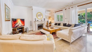 A spacious living room with a fireplace, comfortable seating, and a television.