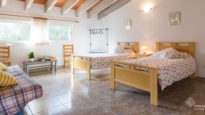 Un dormitorio con dos camas, una mesita, una silla y una ventana con cortinas.