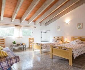 Une chambre avec deux lits, une petite table, une chaise et une fenêtre avec des rideaux.