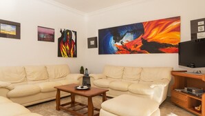 Un salón con sofás color beige, una mesa de centro y un cuadro abstracto grande en la pared.