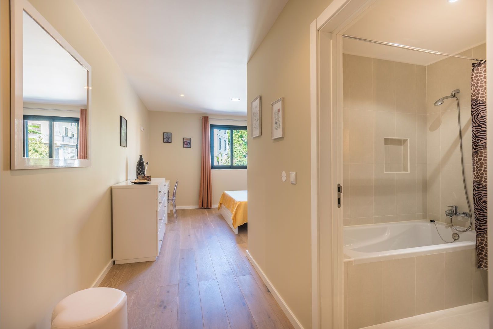 A narrow hallway with a bathroom on the right, featuring a bathtub and shower.
