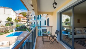 Ein Balkon mit Pool, Esstisch und Sofa.