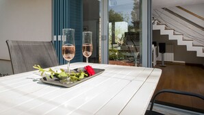 Ein Esstisch mit zwei Gläsern Roséwein, einer roten Rose und einer Serviertschale mit Blättern.