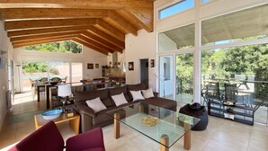 Amplia sala de estar con techo de madera, una mesa de centro de vidrio y un sofá.