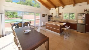 Una cocina amplia con una isla grande, vigas de madera en el techo y vistas a una cancha de tenis.