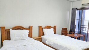 A hotel room with two single beds, a small table, and a chair. - Jitrawadee Hotel (Lampang)