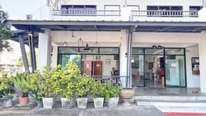 A hotel entrance with a covered porch, potted plants, and a visible interior through glass doors. - Jitrawadee Hotel (Lampang)
