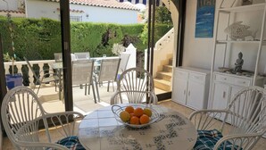 Un comedor con una mesa preparada para dos personas, un frutero y sillas blancas.
