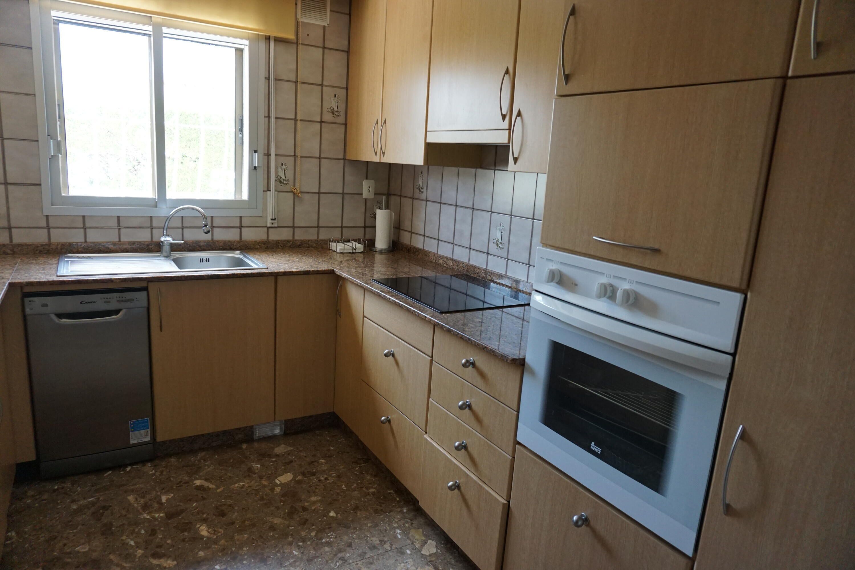 A kitchen with wooden cabinets, a dishwasher, a stove, and a window.