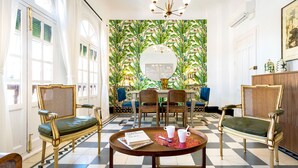 A room with a checkered floor, a round table with chairs, a mirror, and a patterned wallpaper. - Genteel Home Romanilla (Granada)
