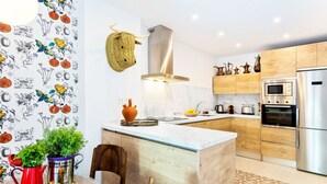 A modern kitchen with wooden cabinets, a stainless steel refrigerator, and a central island with a glass top. - Genteel Home Romanilla (Granada)