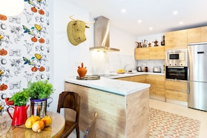 A modern kitchen with wooden cabinets, a stainless steel refrigerator, and a central island with a glass top.