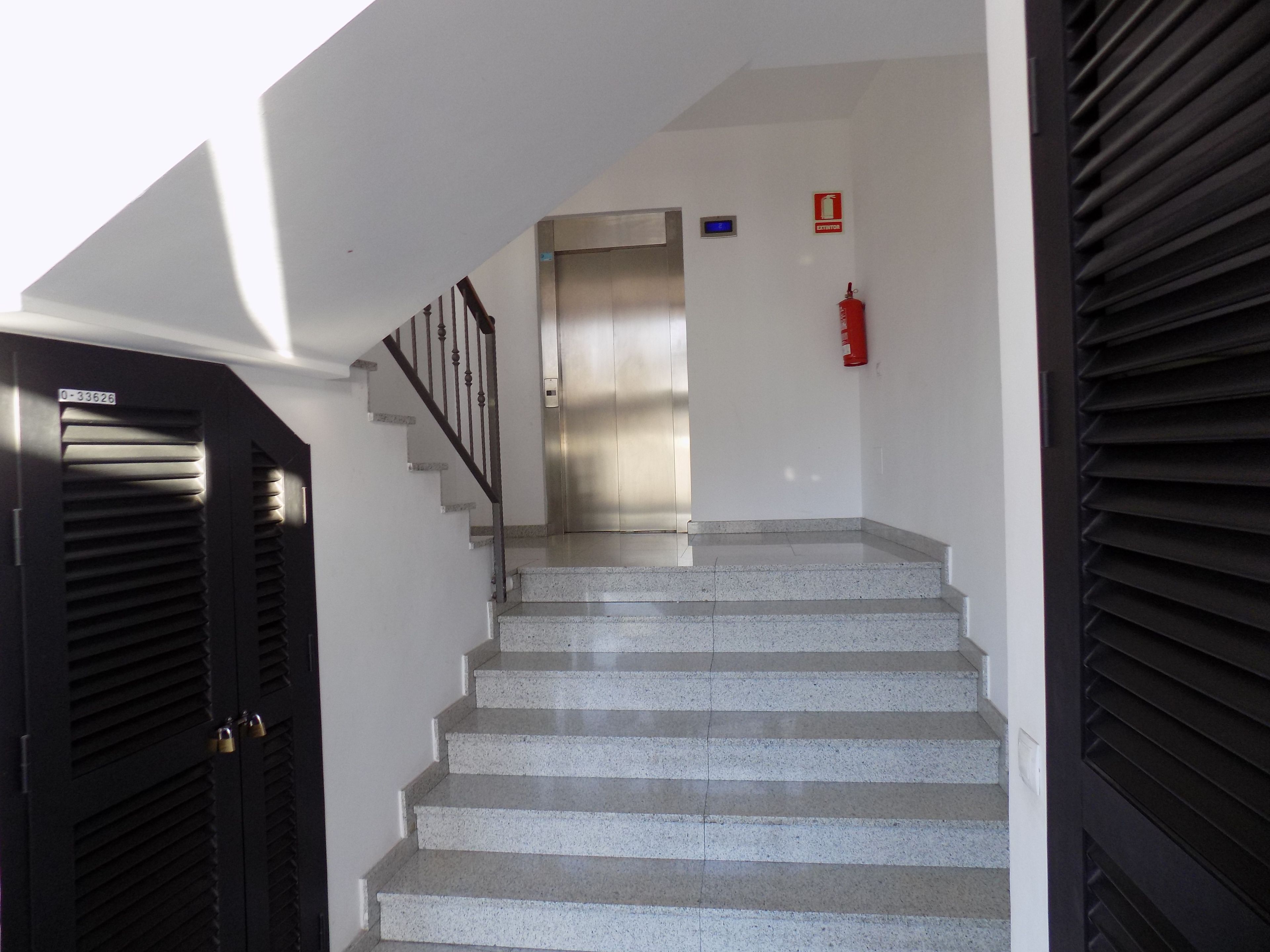 Eine Treppe mit Metallgeländer, einem Feuerlöscher und einer Tür mit Schloss.