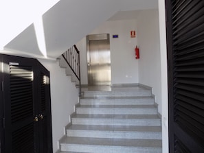 A staircase with a metal handrail, a fire extinguisher, and a door with a lock.