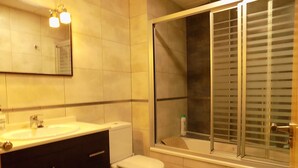 Een badkamer met een wastafel, toilet en een douchegedeelte met een raam.
