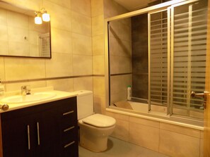 Un baño con lavamanos, inodoro y zona de ducha con ventana.