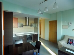 A modern kitchen with a dining area, a sofa, and a television. - Penthouse with sea view in the center of Fuerteventura, Puerto del Rosario (Puerto del Rosario)