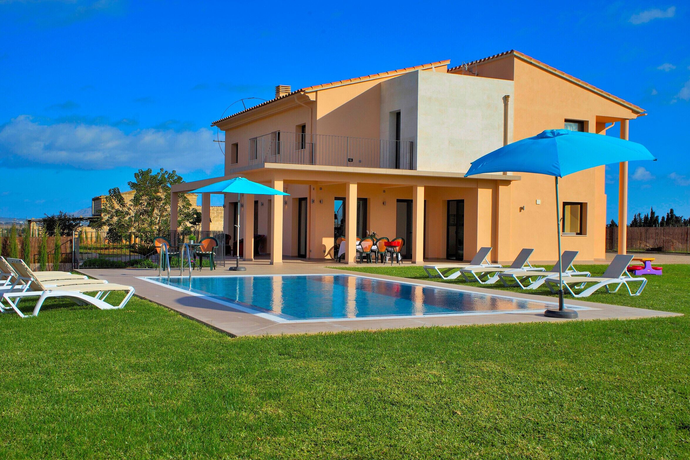 Ein zweistöckiges Haus mit Pool, Sitzgelegenheiten im Freien und einer überdachten Terrasse.