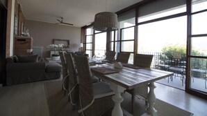 Un comedor con una mesa grande, sillas de mimbre y un ventilador de techo.