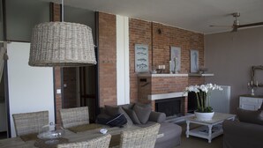 Una sala de estar con chimenea de ladrillo, muebles de mimbre y ventilador de techo.